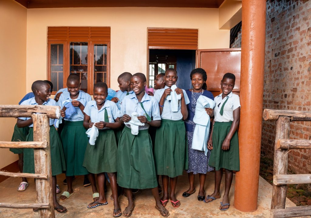 A group of girls pose for a photo infront of an MHM room