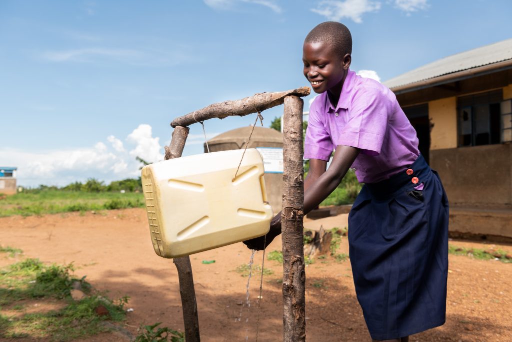 A girl washing her hands from a tippy tap