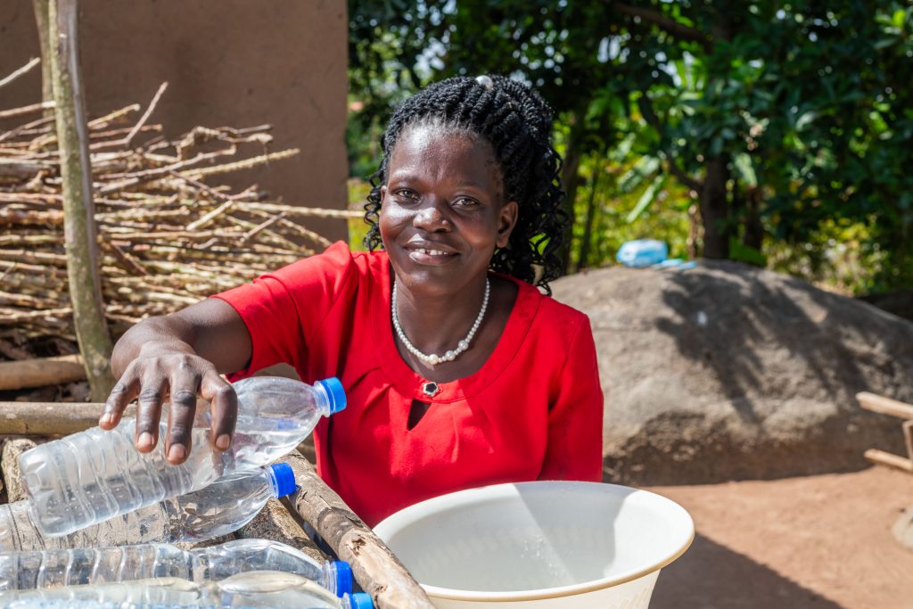 A mother places SODIS bottles onto a rack