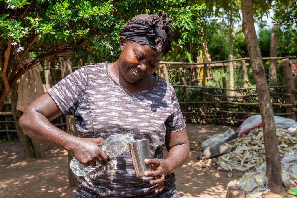 A mother pours water into a metallic cup