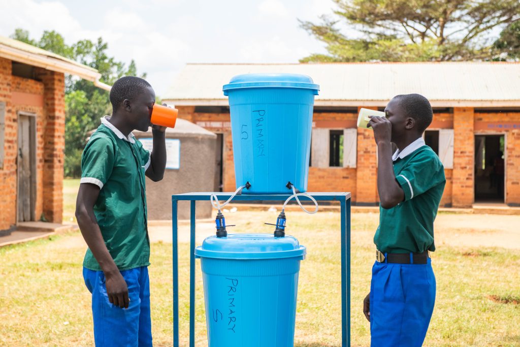 Two Boys drinking water from a sawyer filter