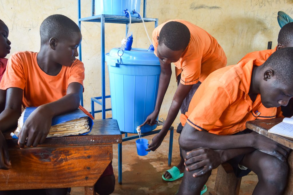 A student of Japiemonen primary school draws water from a SAWYER filter