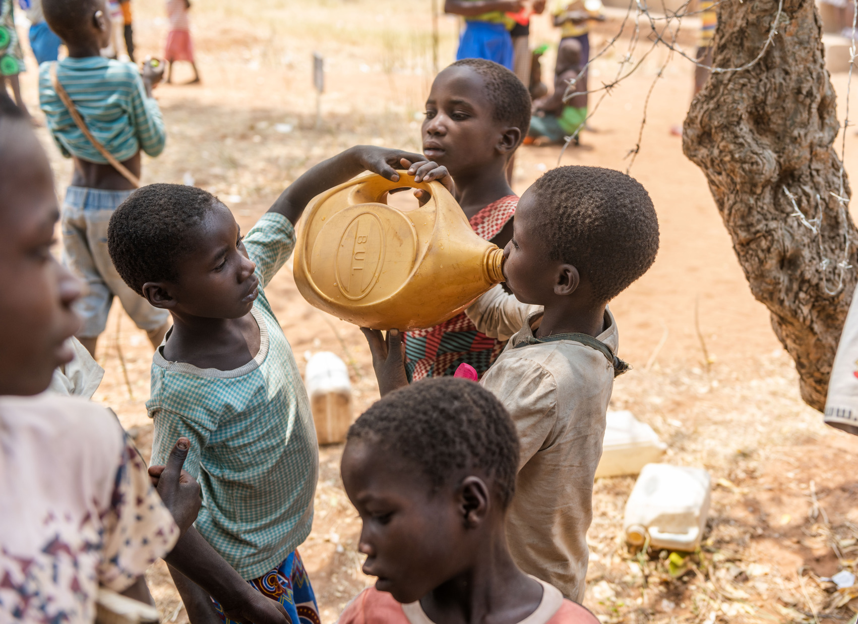 Children taking turns to drink from one jerrycan