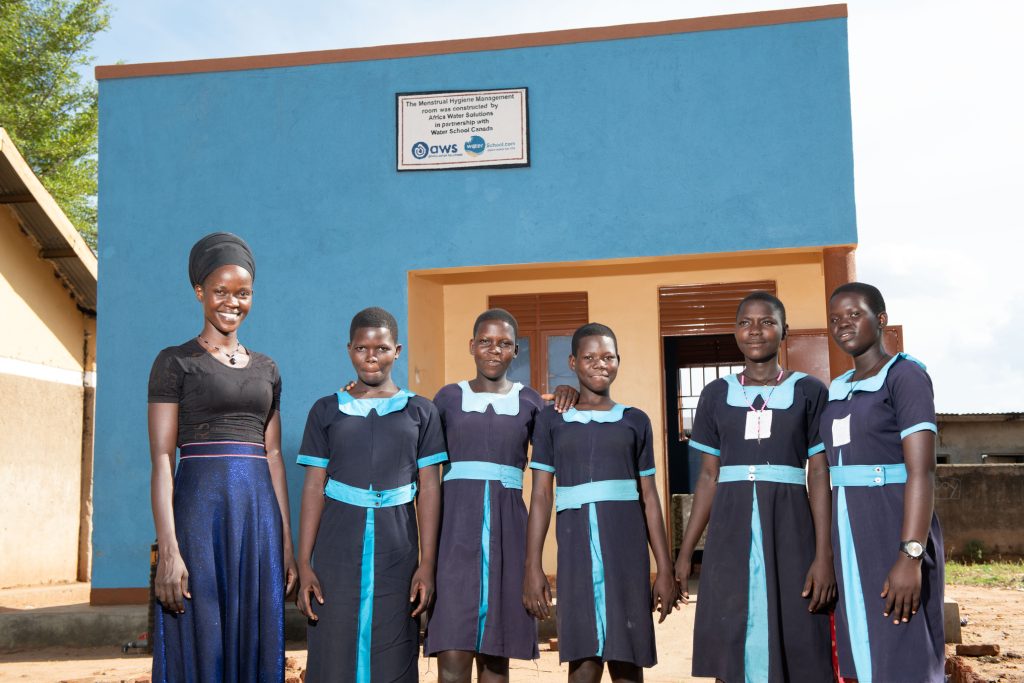 Girls together with a senior woman standing infront of the newly constructed MHM room