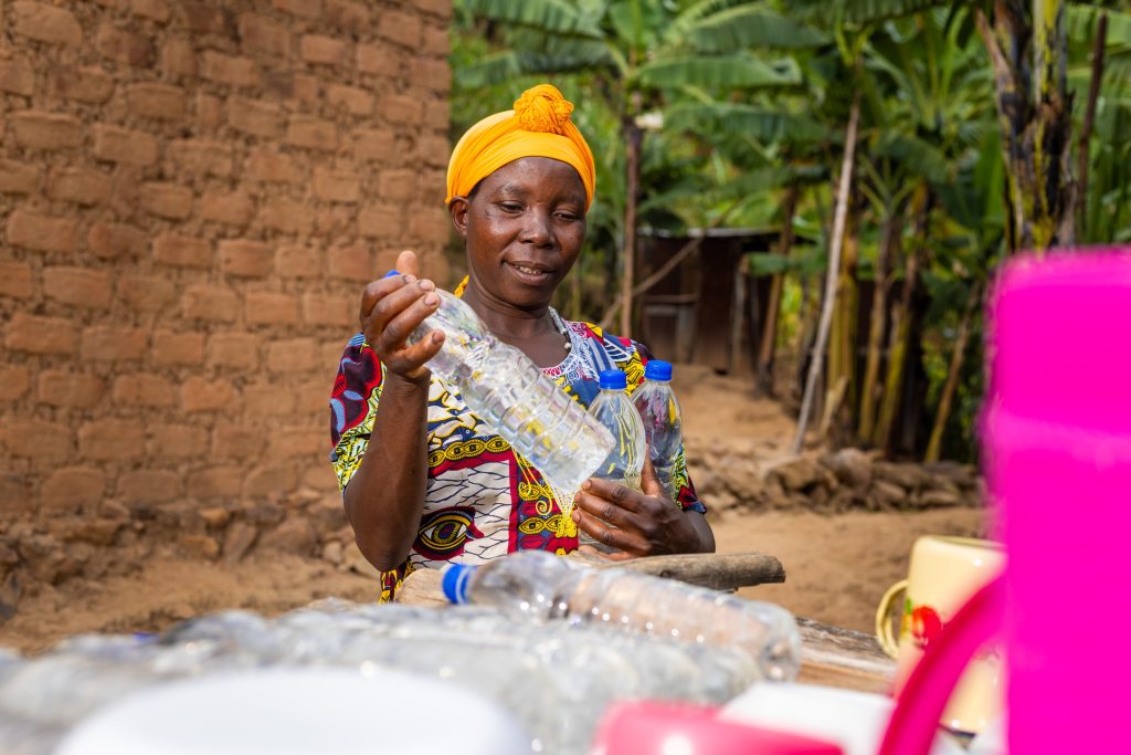 Ponsiano's wife placing SODIS bottles on a rack