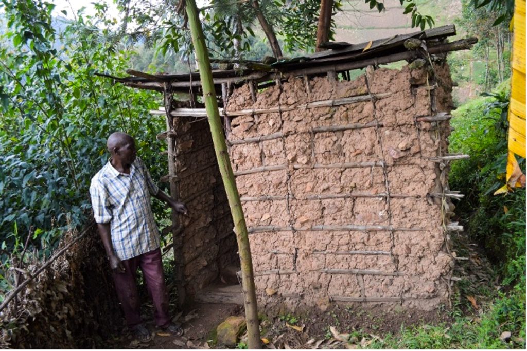 Ponsiano stands next to his old latrine