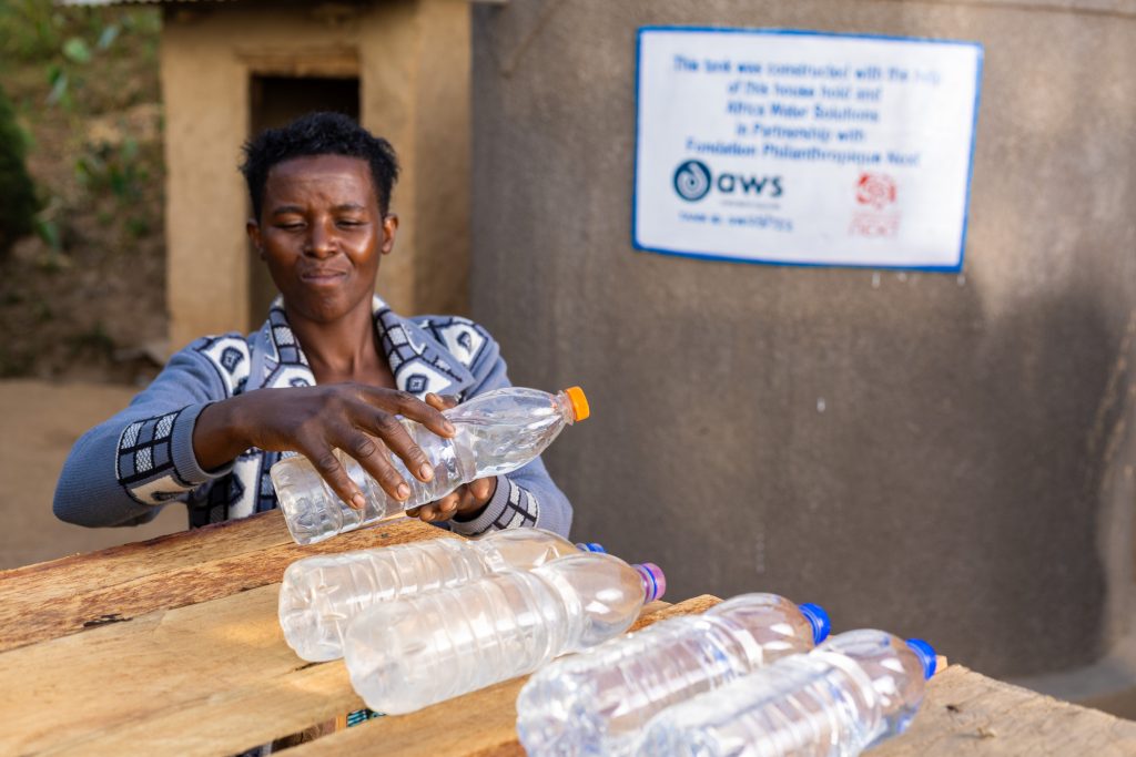 Emmauel's wife place SODIS bottles on a rack